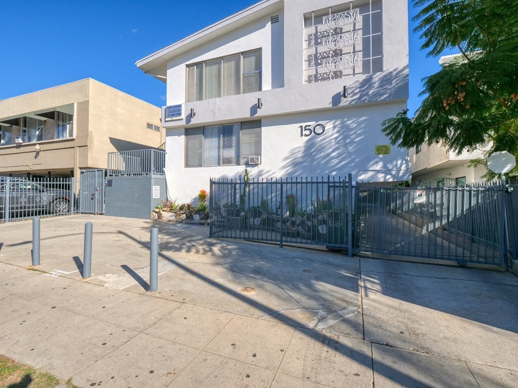 a white building with a gate and a sidewalk in front of it