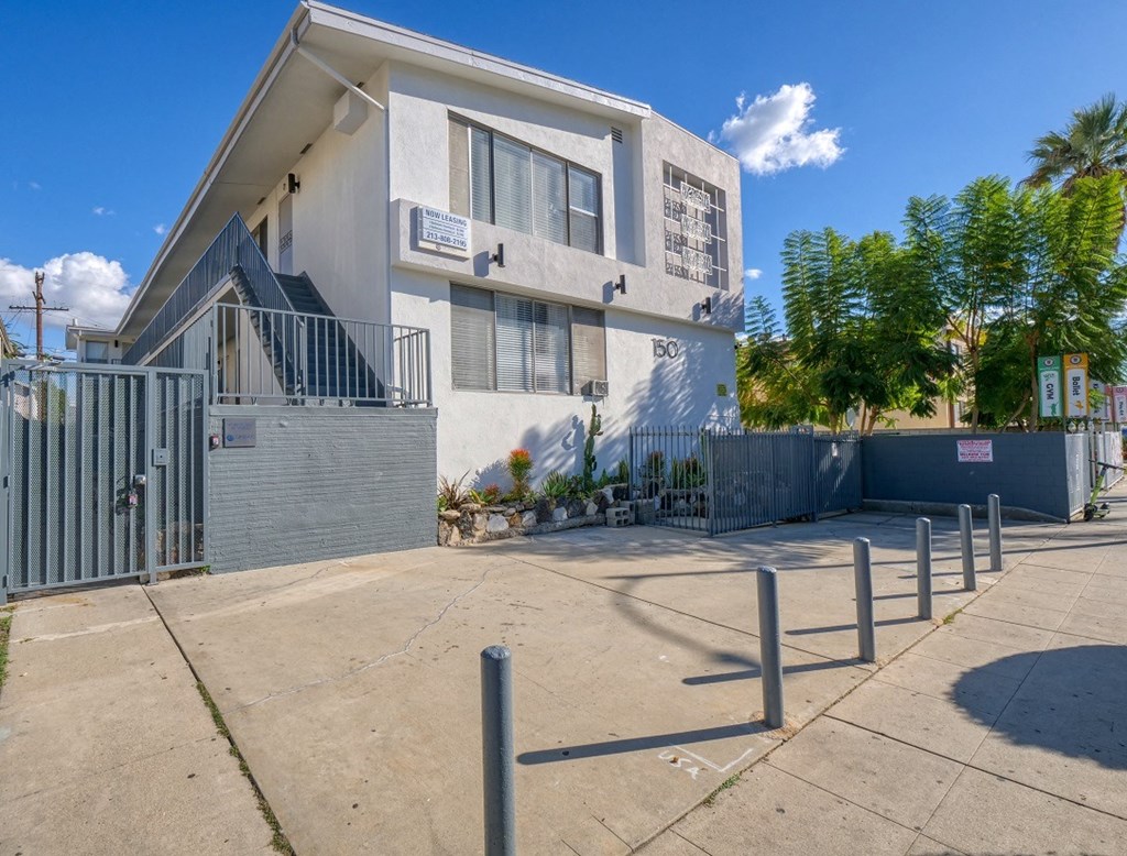 a white building with a fence and a sidewalk in front of it
