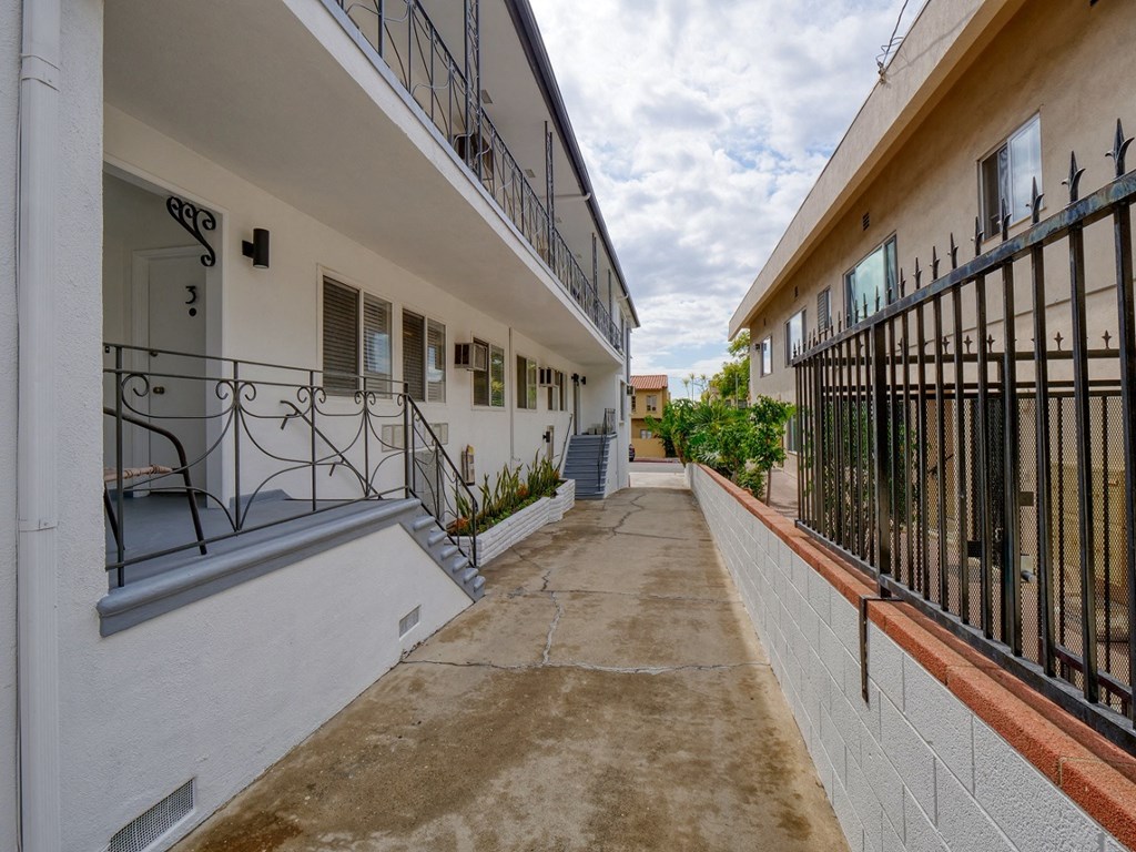 the walkway between two apartment buildings with wrought iron gates and balconies