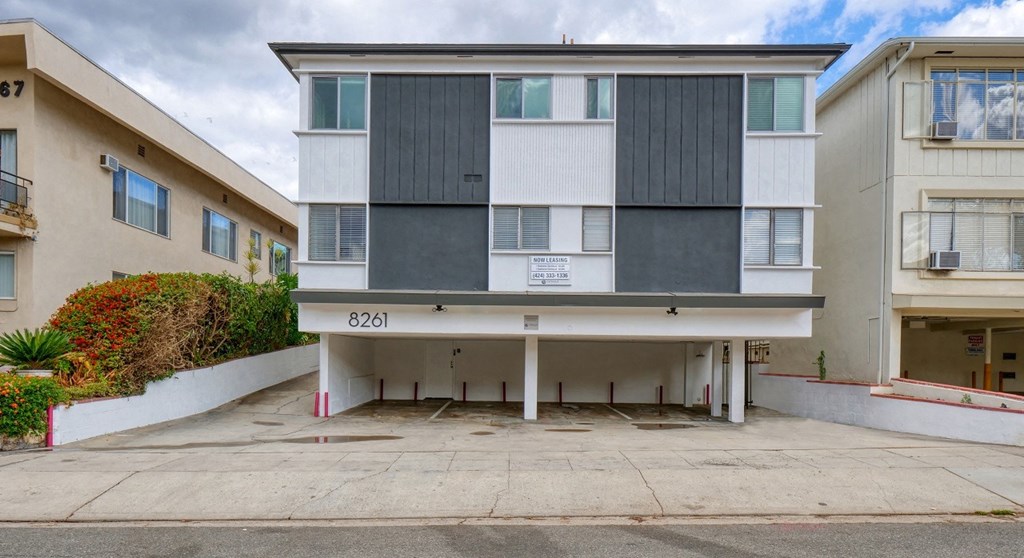 a white and gray apartment building with a parking lot