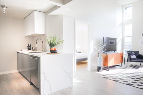 a kitchen with an island and a living room with a couch and a tv