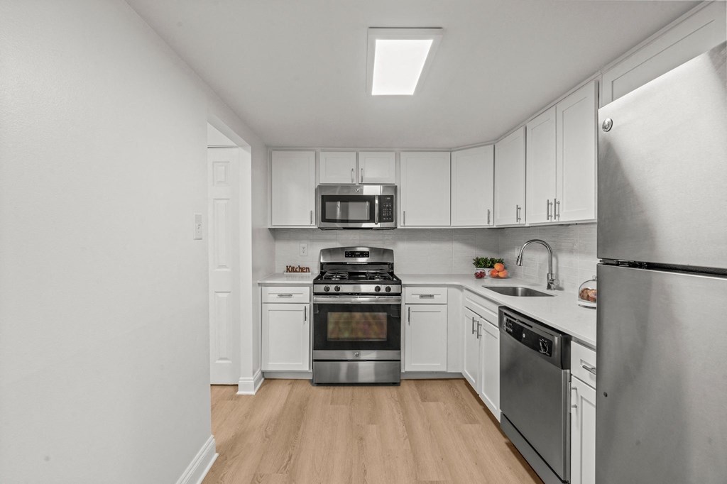 A kitchen with a stainless steel refrigerator, stove, and oven.