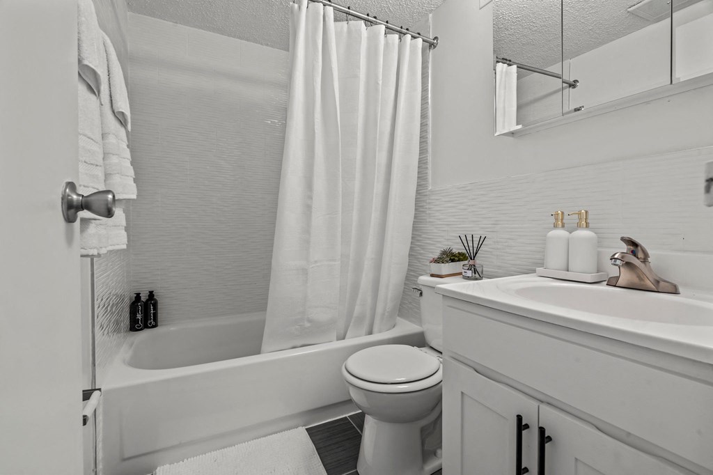 a white bathroom with a shower toilet and sink