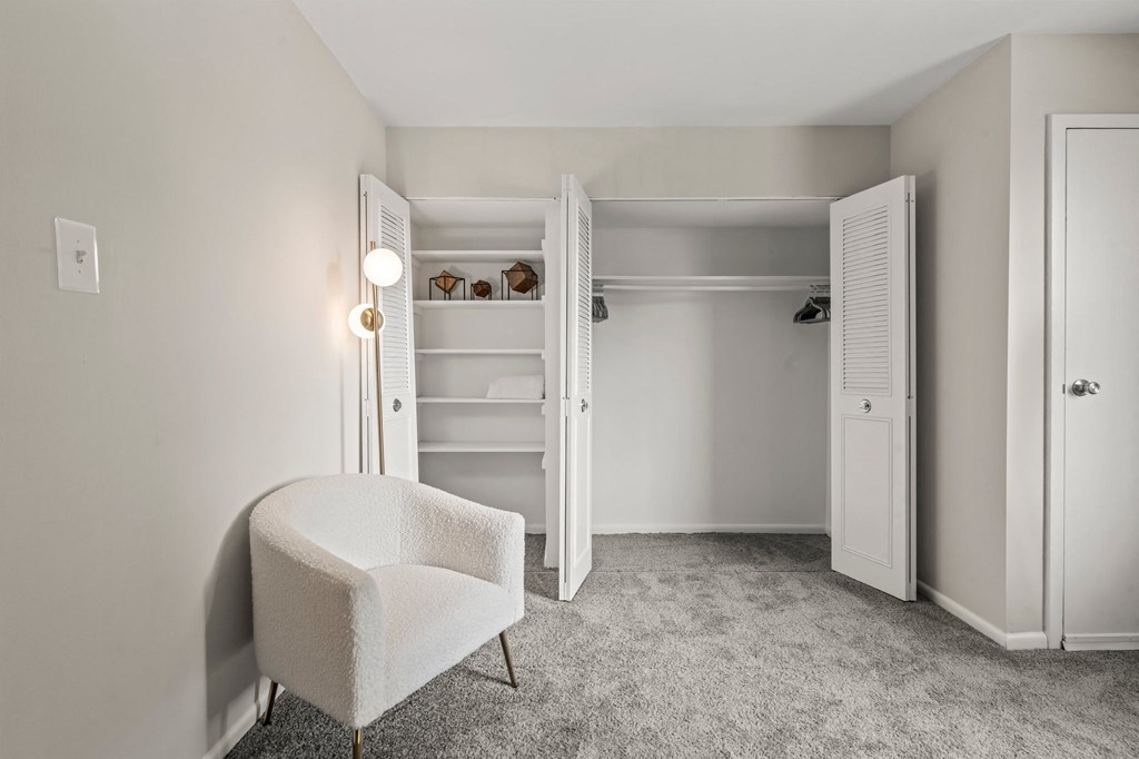 a bedroom with a chair and a closet with shelves