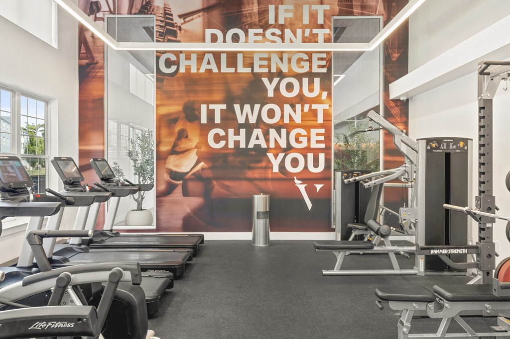 A gym with treadmills, weights and a sign that says "If it doesn't challenge you, it won't change you.".