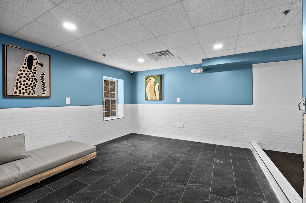 A room with a grey sofa and a painting of a dog on the wall.