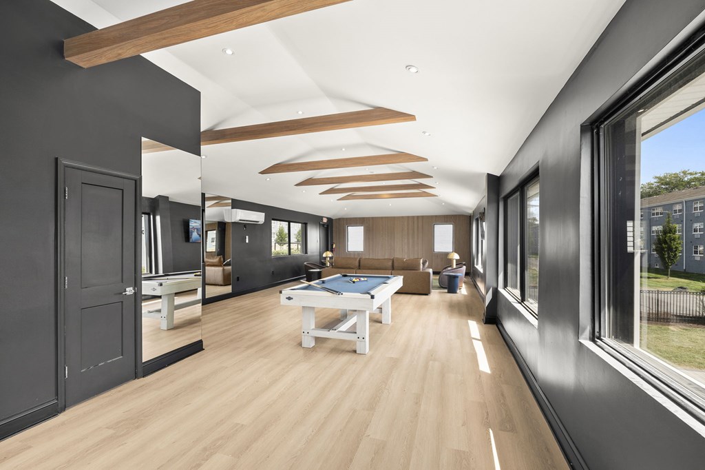 A modern living room with a pool table and a view of the backyard.