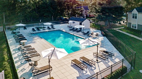 A large outdoor swimming pool surrounded by sun loungers and umbrellas.