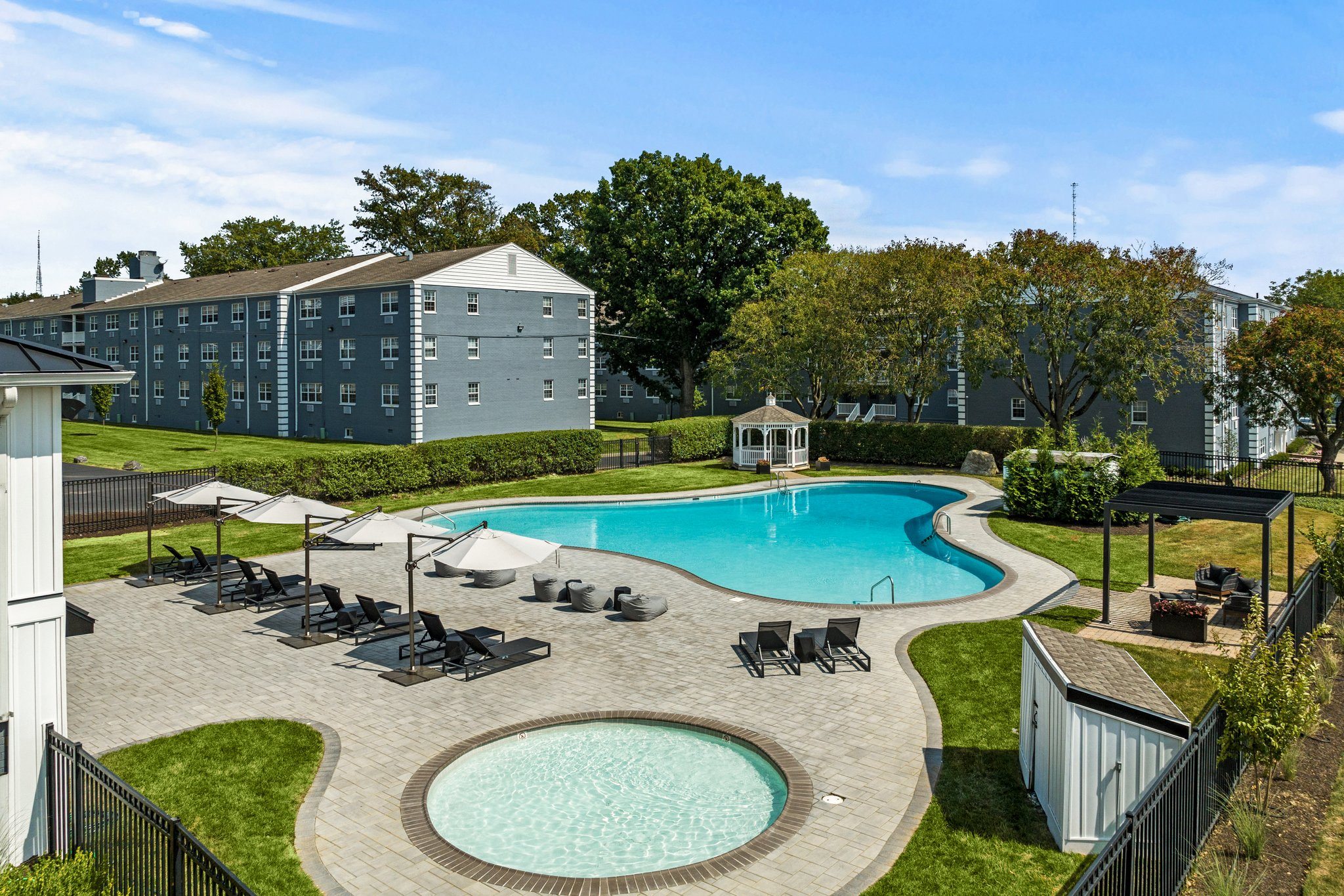 a swimming pool with lounge chairs and umbrellas in front of a building  at Chestnut Hill Village, Philadelphia, Pennsylvania