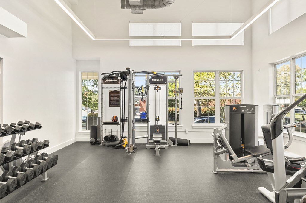 A well lit gym with a variety of equipment.