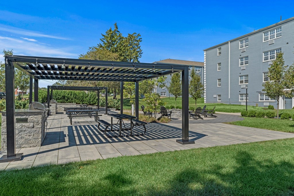 a picnic area with benches and a fire pit at the enclave at woodbridge apartments in sugar  at Chestnut Hill Village, Philadelphia
