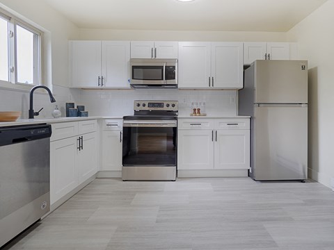 a kitchen with white cabinets and stainless steel appliances