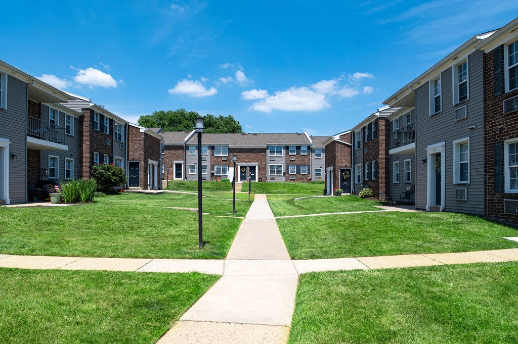 A sunny day at a residential area with apartment buildings and a walkway in the foreground.