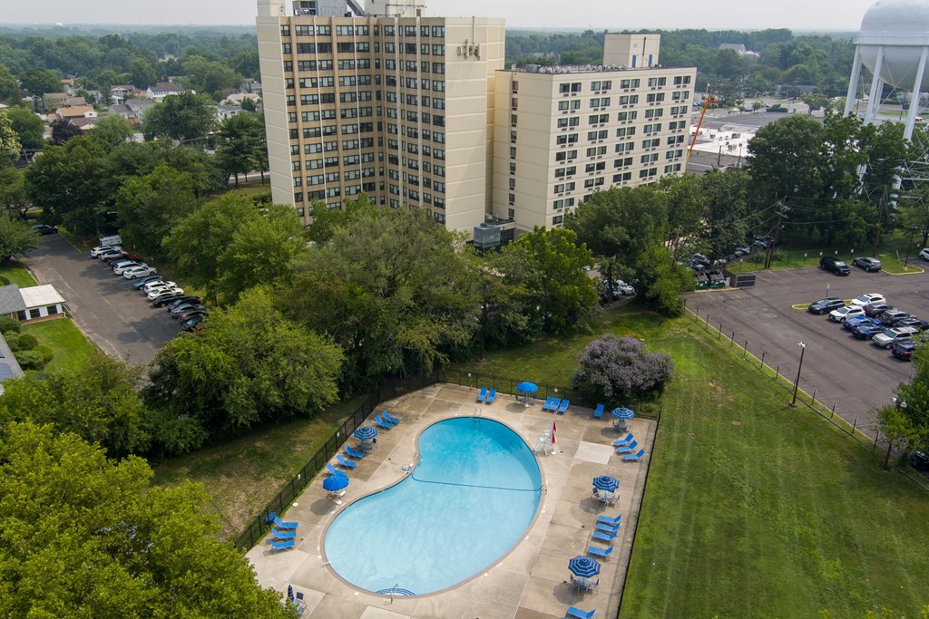 A large swimming pool surrounded by lawn chairs and trees.