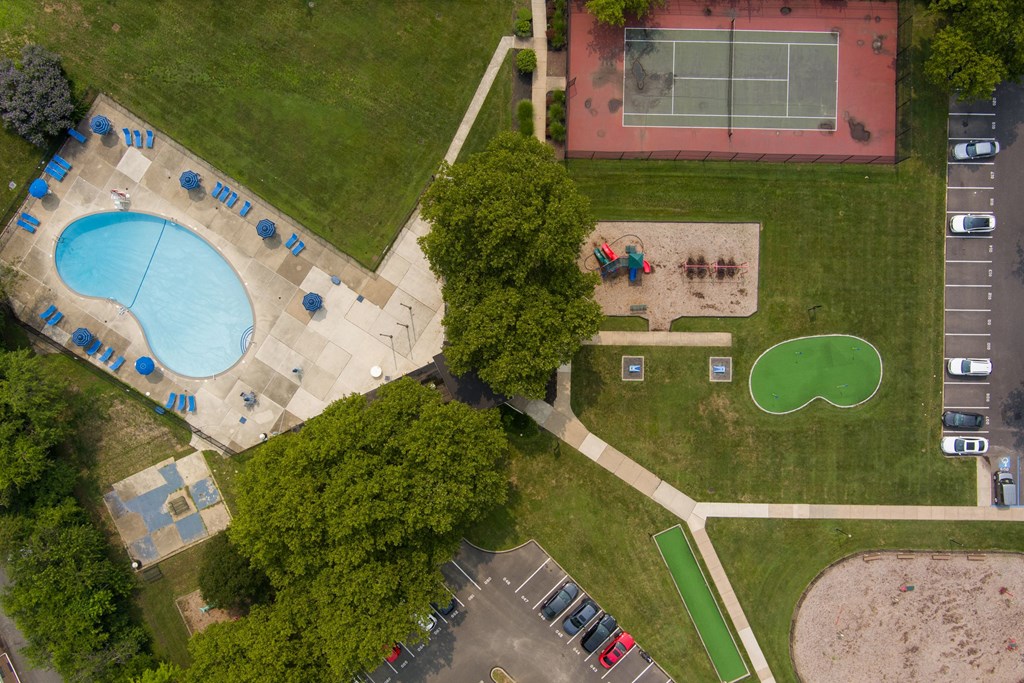 A park with a tennis court, a basketball court, a swimming pool, and a playground.