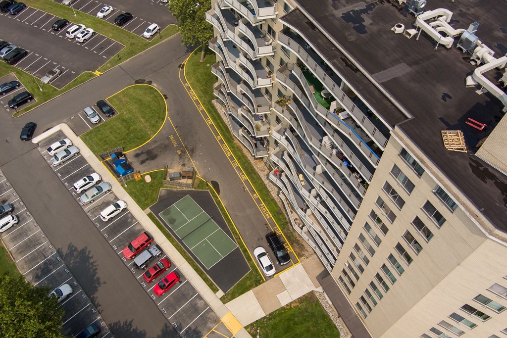 A parking lot with cars and a tennis court in front of a building.