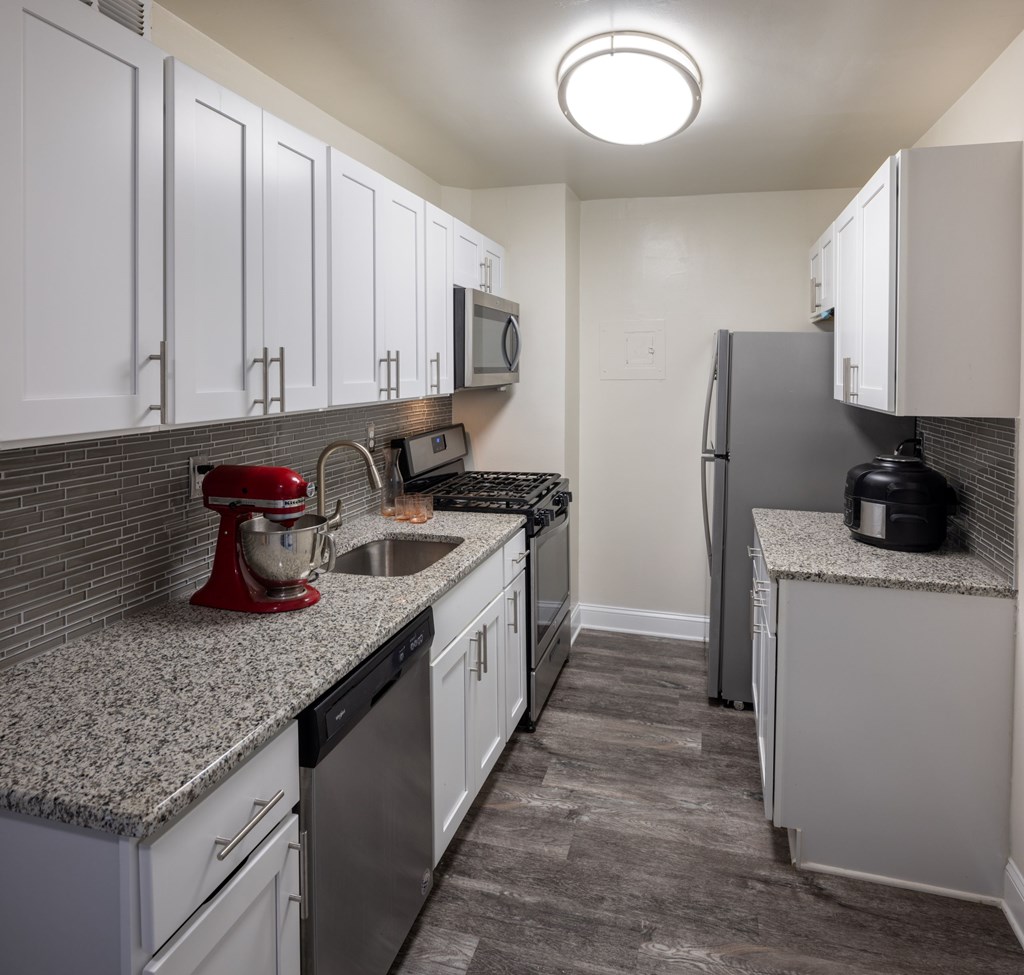 A kitchen with white cabinets and a red mixer.