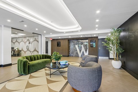 A modern waiting area with a green sofa, grey armchair, and a coffee table.
