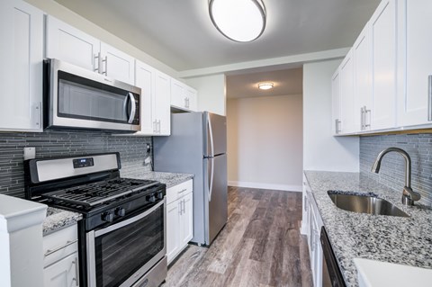 A kitchen with a black stove top oven and a black microwave above it.