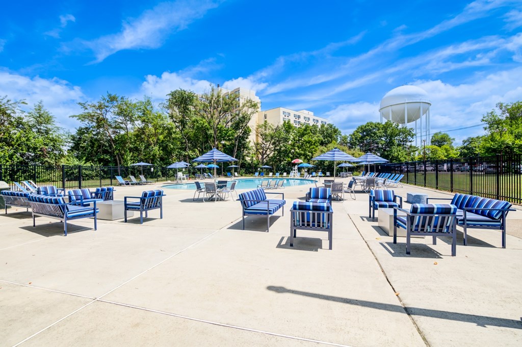A sunny day at the pool with blue chairs and a water tower in the background.