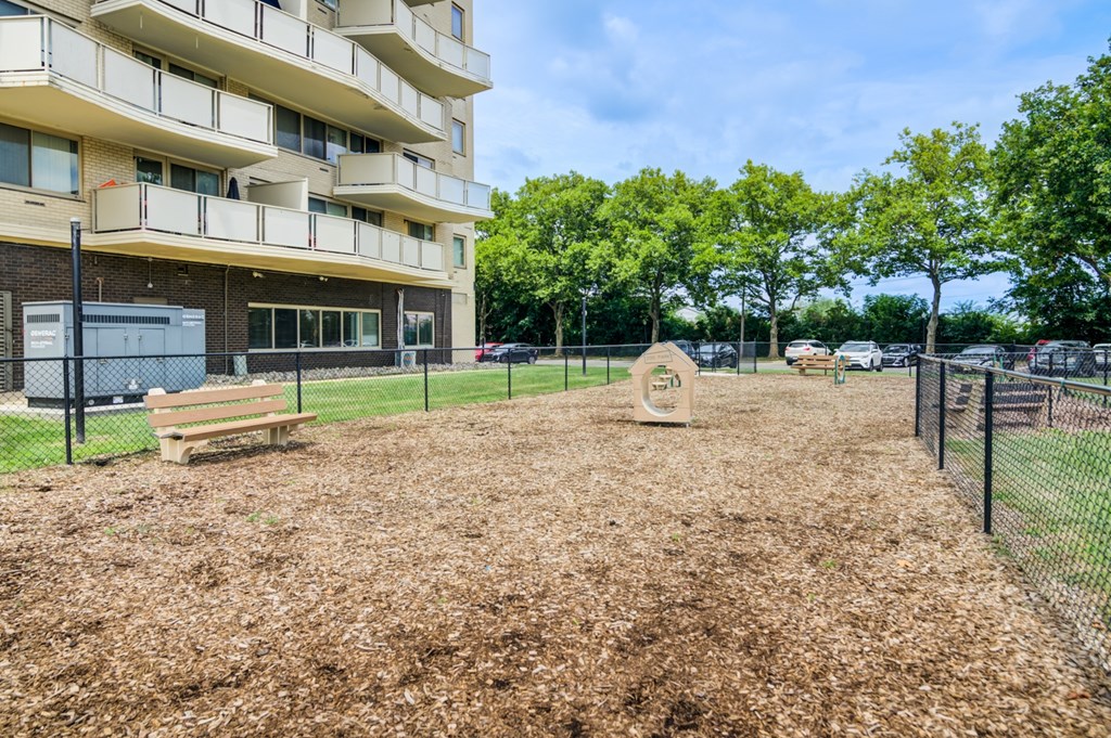 A playground area with a sandbox and a bench in front of a residential building.