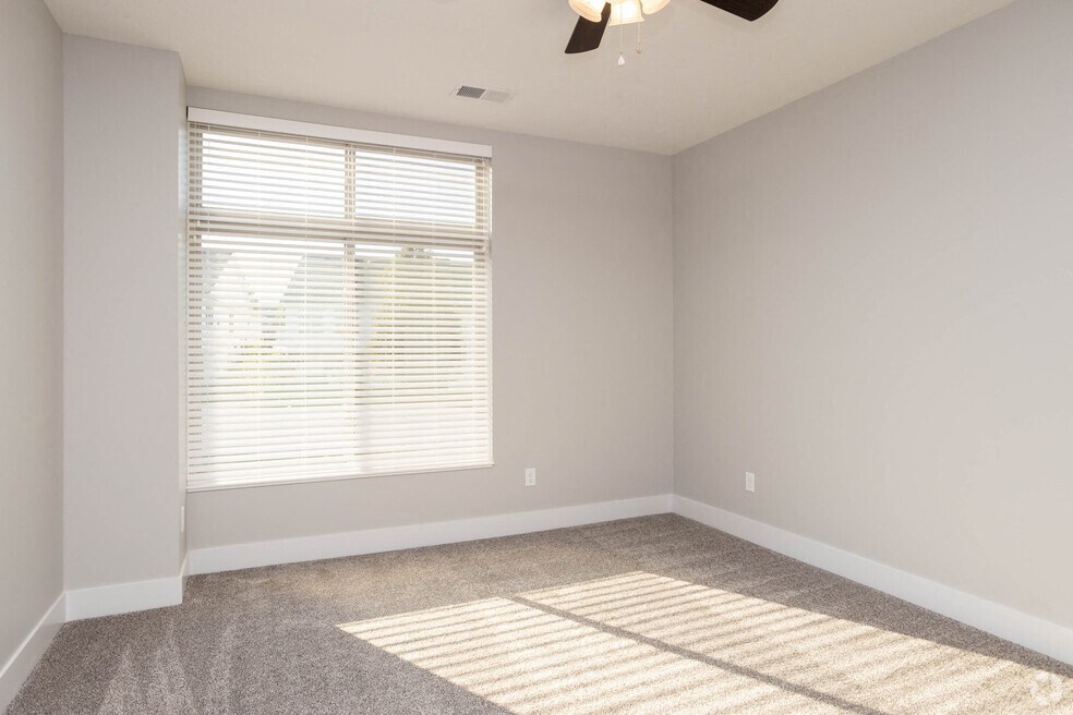an empty room with a window and a ceiling fan