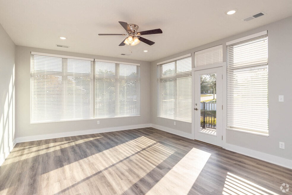 an empty living room with a ceiling fan and windows