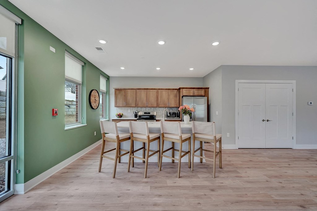 a kitchen with a long bar with chairs and a green wall