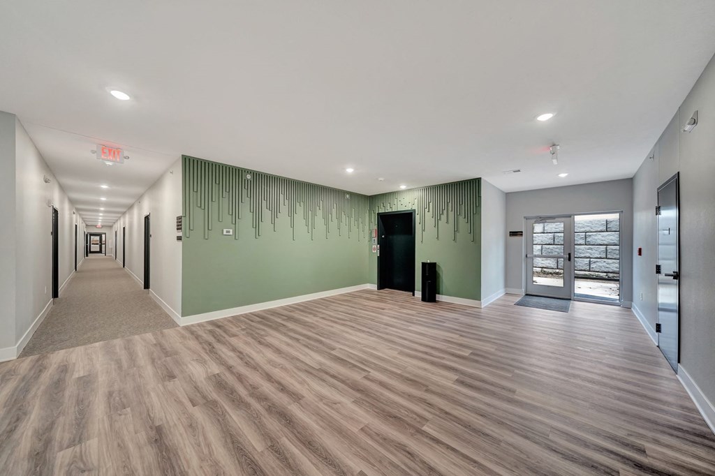a long hallway with green walls and wooden floors and a glass door