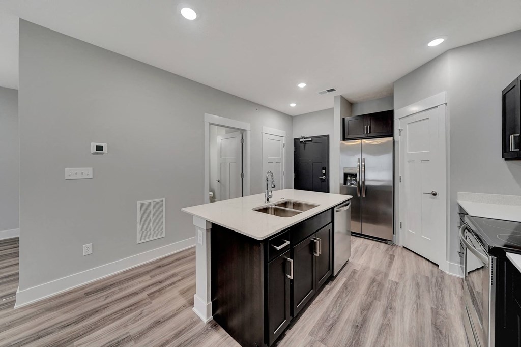 a kitchen with a large island and a stainless steel refrigerator