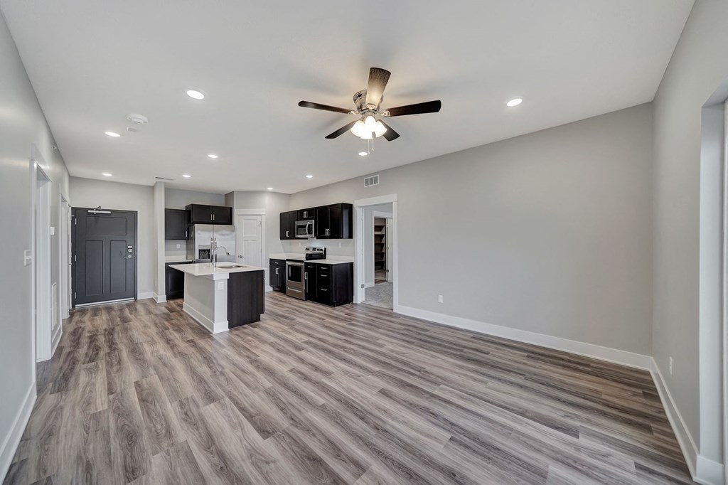 an empty living room and kitchen with a ceiling fan