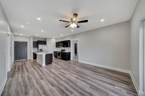 an empty living room and kitchen with a ceiling fan
