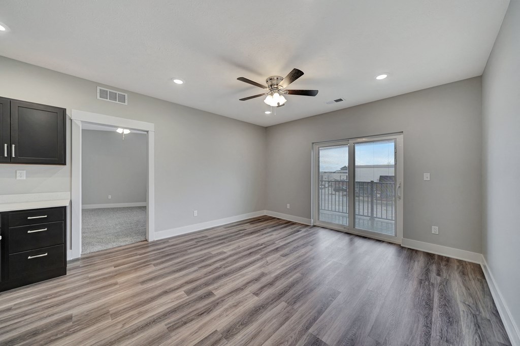 an empty living room with a ceiling fan and a window