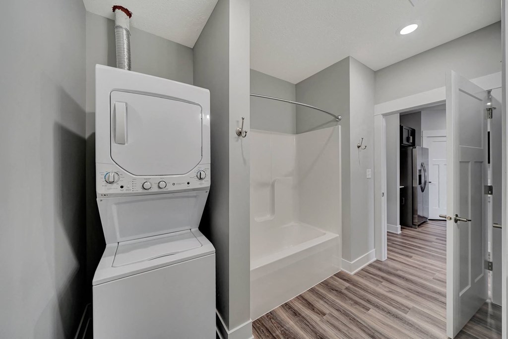 a white washer and dryer in a room with a shower and a bathroom