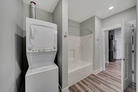 a white washer and dryer in a room with a shower and a bathroom