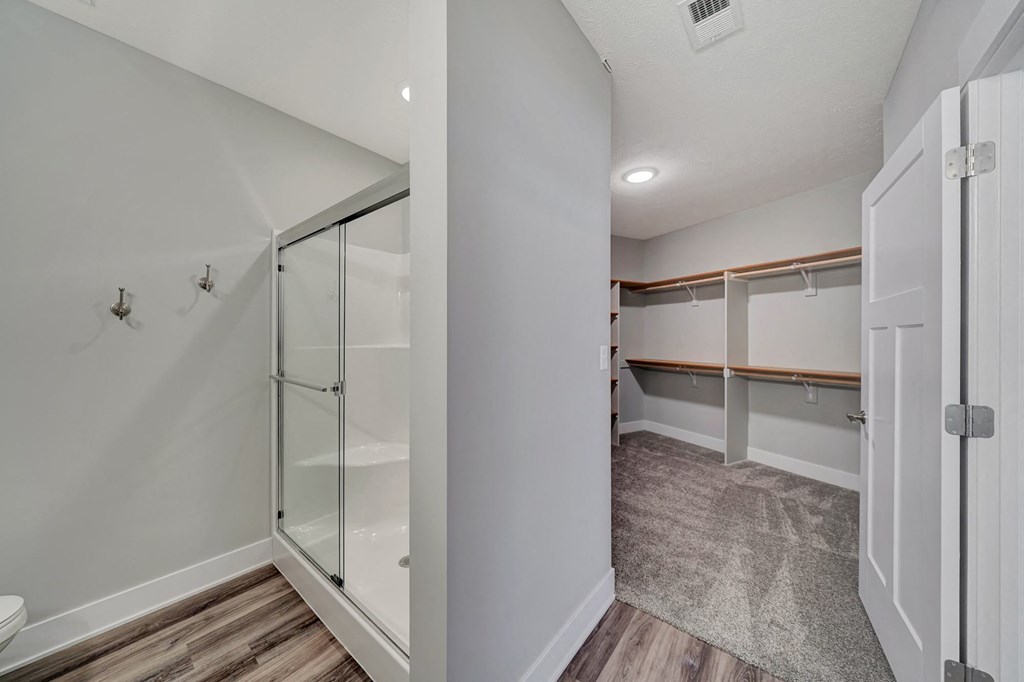 a walk in closet with a mirrored closet door and a shower