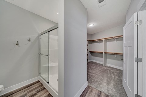 a walk in closet with a mirrored closet door and a shower