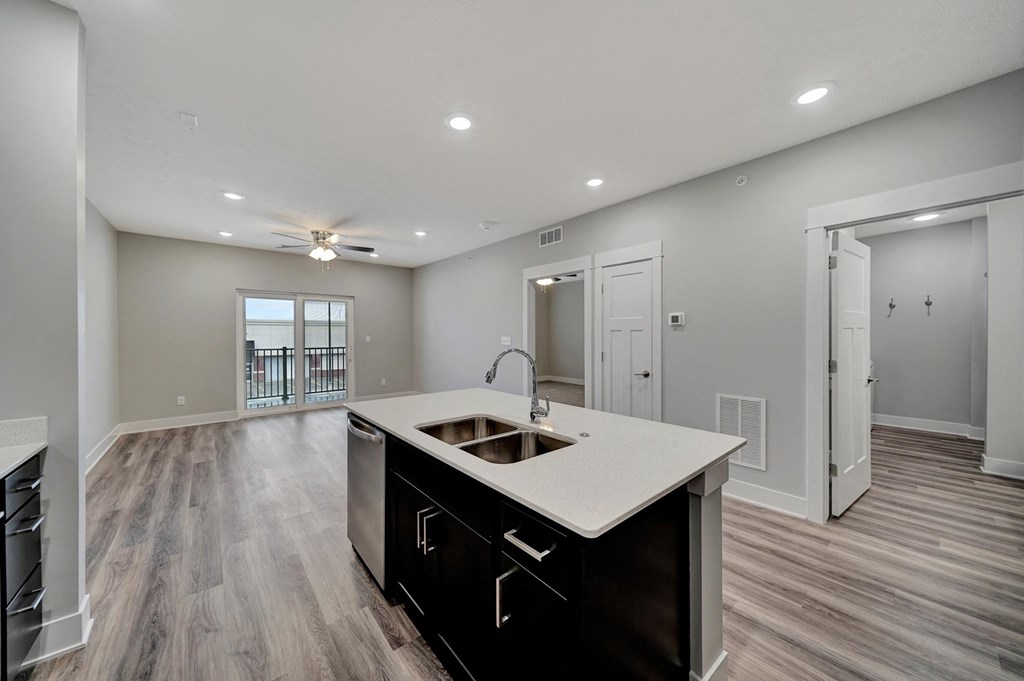an open living room and kitchen with a sink and a ceiling fan