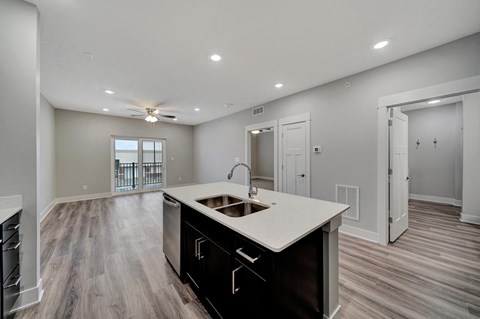 an open living room and kitchen with a sink and a ceiling fan
