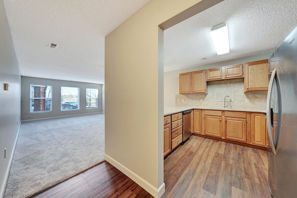 an empty kitchen with wooden cabinets and a stainless steel refrigerator