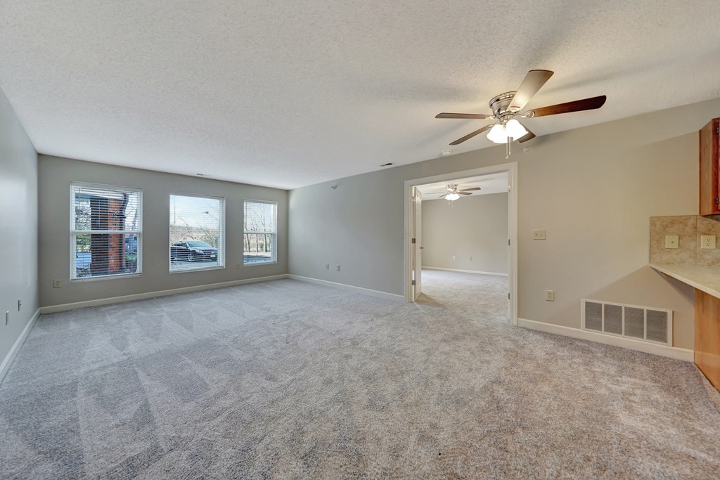 an empty living room with a ceiling fan and a window