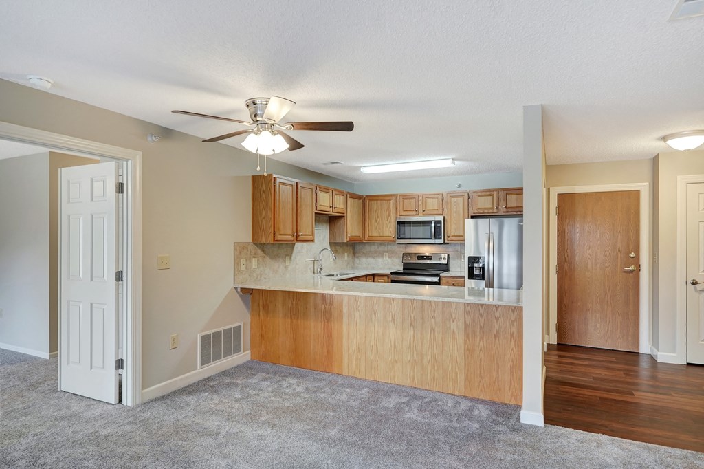 an empty living room and kitchen with a ceiling fan