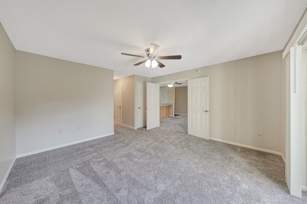 a spacious living room with carpet and a ceiling fan