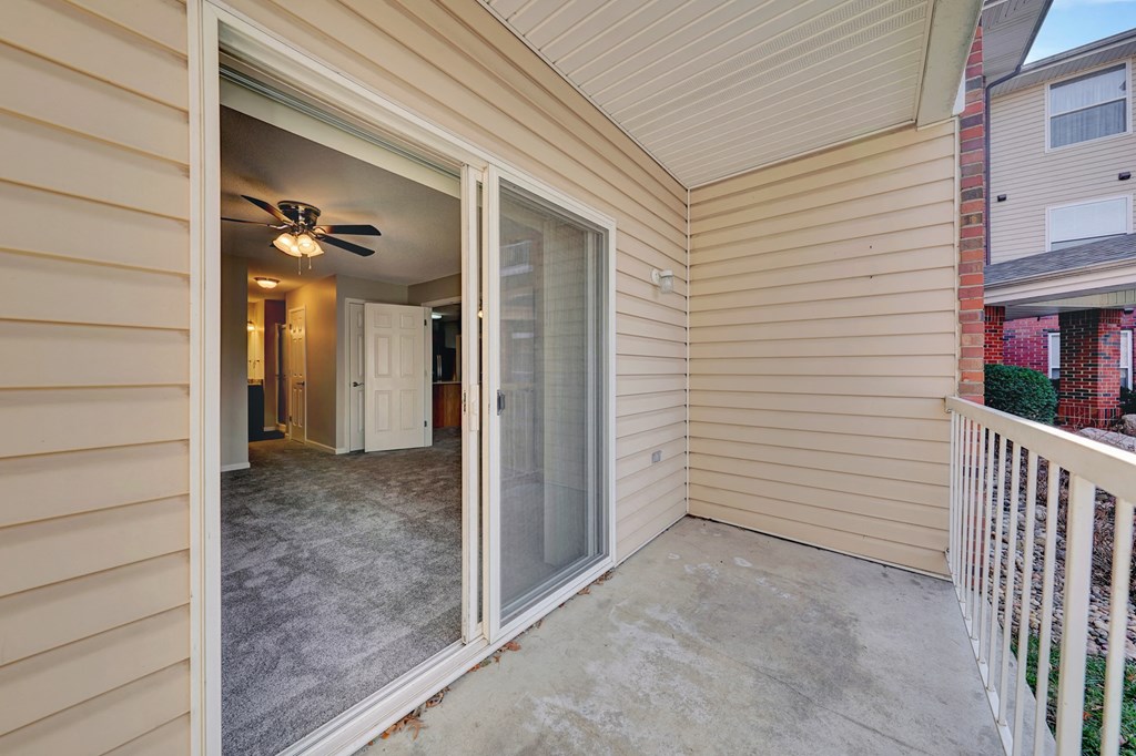 a patio with a ceiling fan and a door to a hallway