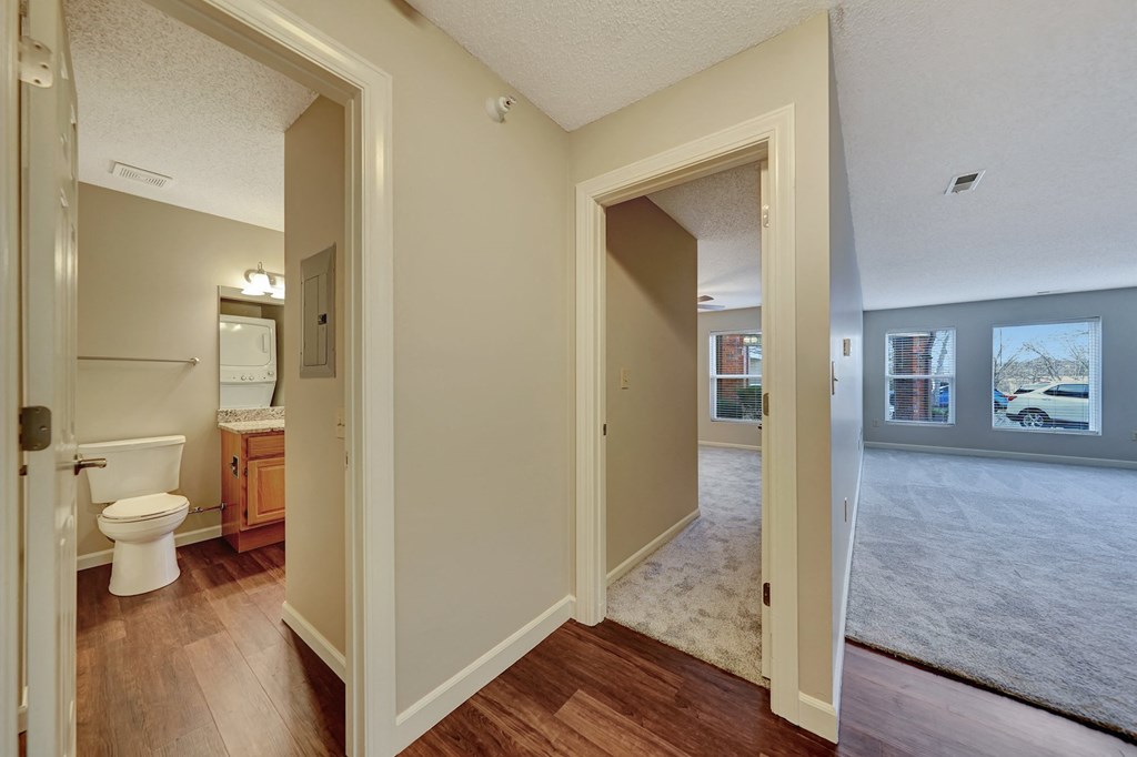 an empty living room and bathroom with a toilet and a sink