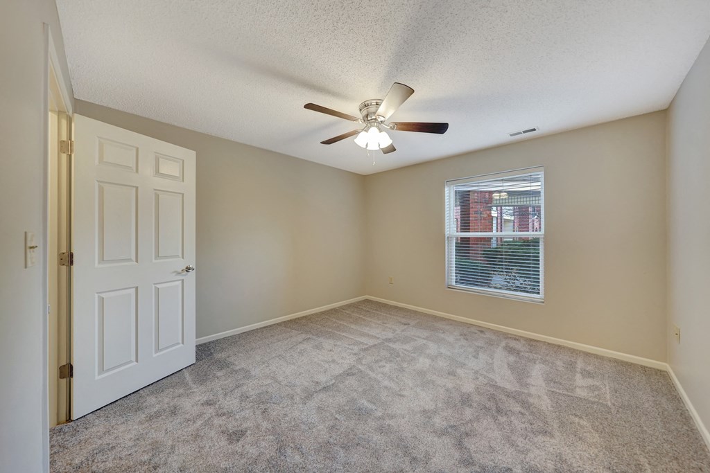 an empty living room with a ceiling fan and a window