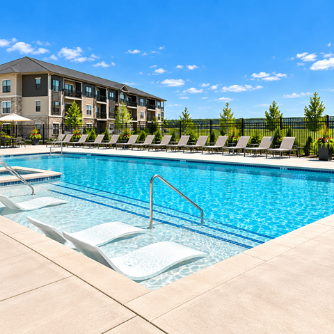 A swimming pool with lounge chairs and a building in the background.