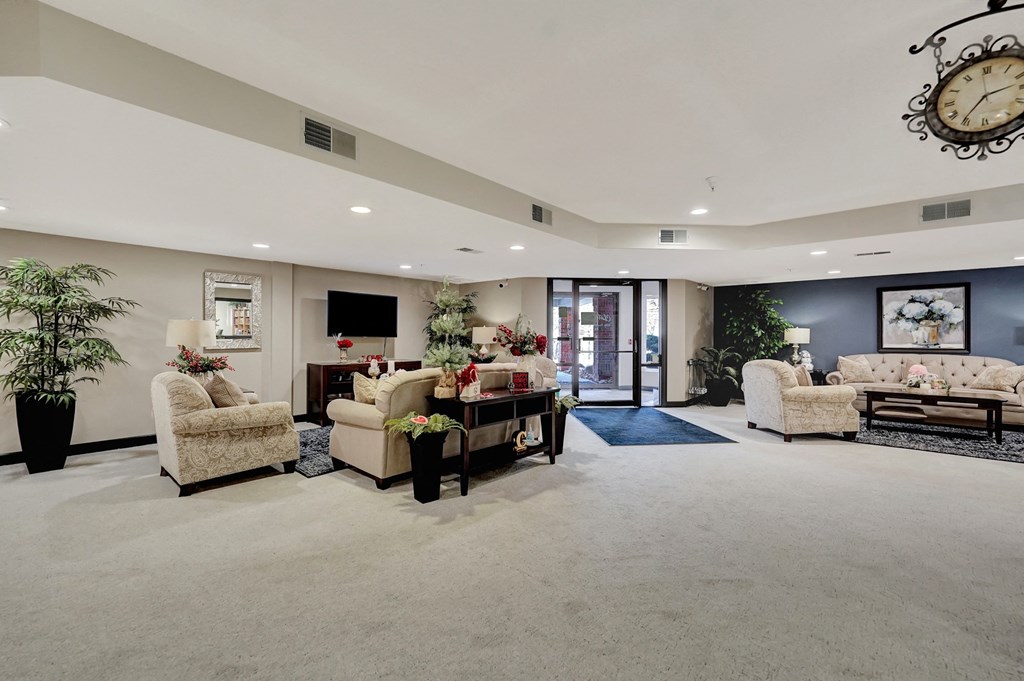 a large living room with couches and chairs and a clock on the wall