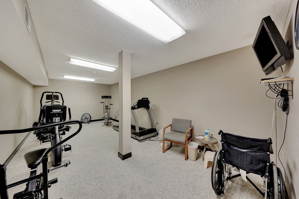 a home gym with a wheelchair and a tv on the wall