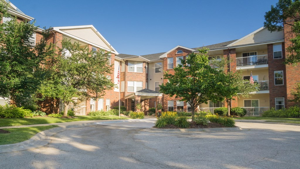 an apartment building with a parking lot and trees